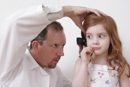 Kinderarzt untersucht die Ohren eines Mädchens