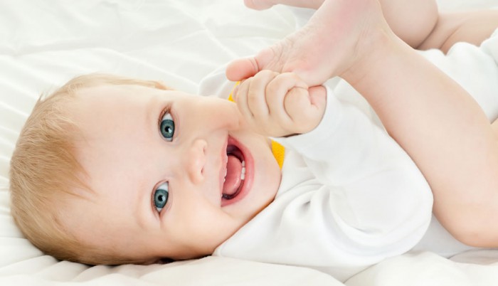 Ein lächelndes Baby zeigt erste Zähne