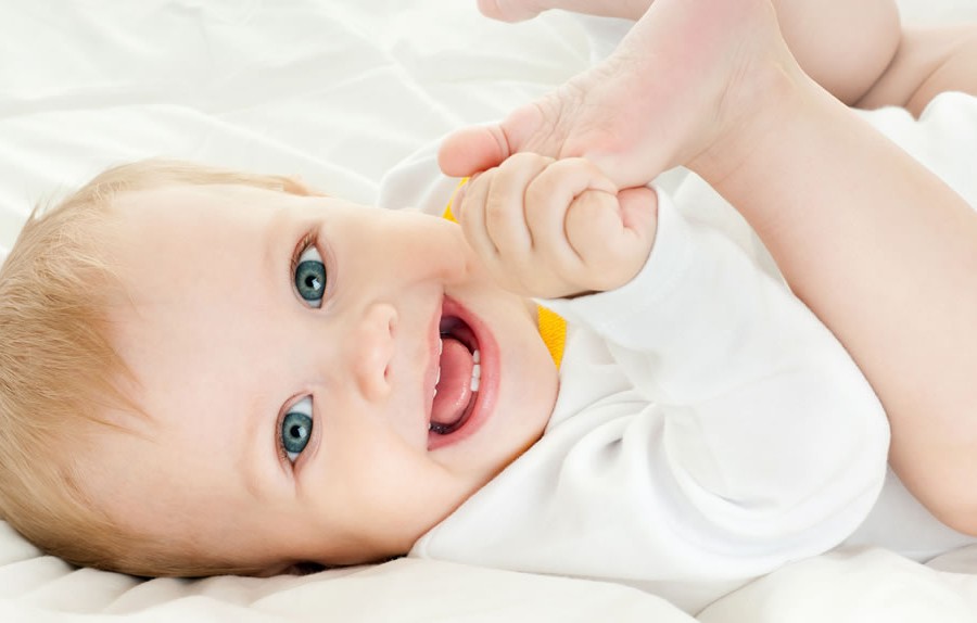 Ein lächelndes Baby zeigt erste Zähne