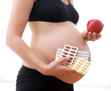 Schwangere mit Ergaenzungspraeparaten und vitaminreicher Ernaehrung