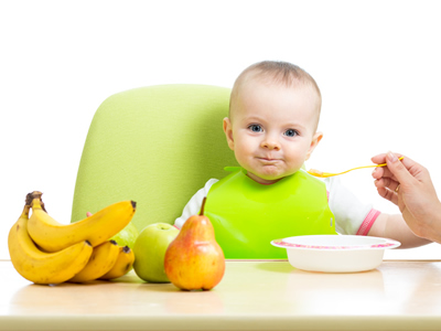 Ein Baby sitzt am Tisch mit Obst