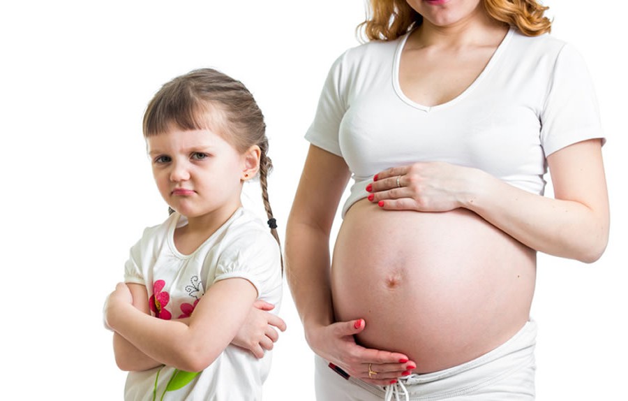 Ein beleidigtes Kind steht vor einer schwangeren Frau